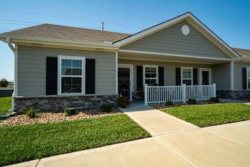 A house with a grey siding and a white fence.