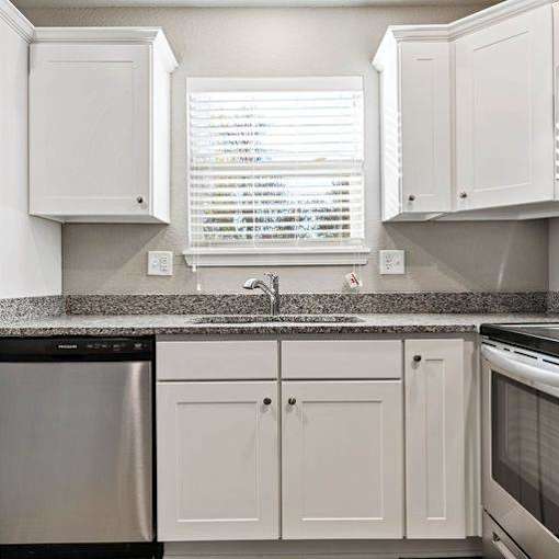A kitchen with white cabinets and a granite countertop.