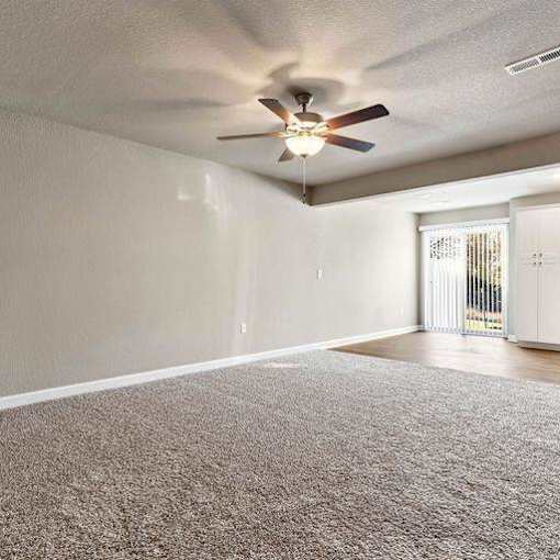 A room with a ceiling fan and carpeted floor.