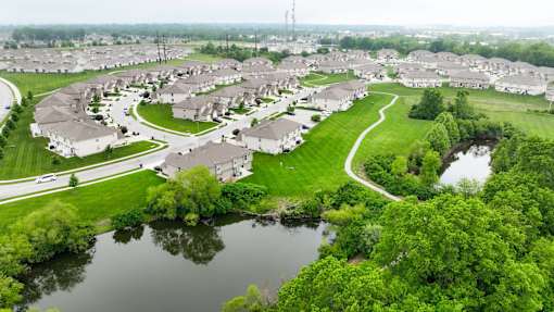 A bird's eye view of a residential area with houses, a river, and a road.
