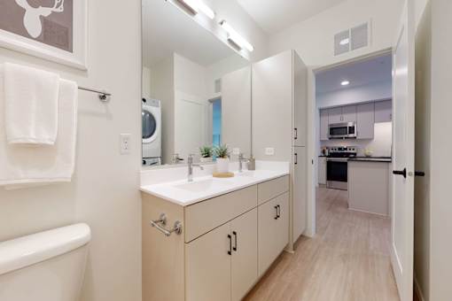 A bathroom with a white tub and a white sink with a mirror above it.