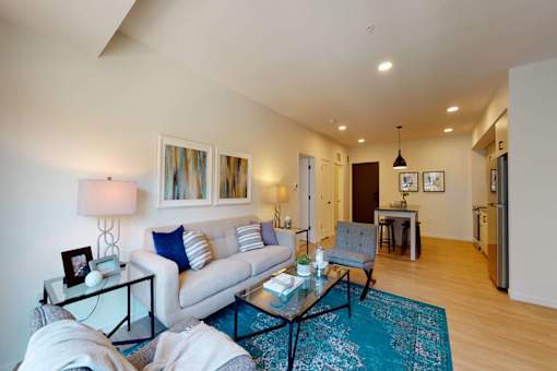 A living room with a white couch and a glass coffee table.