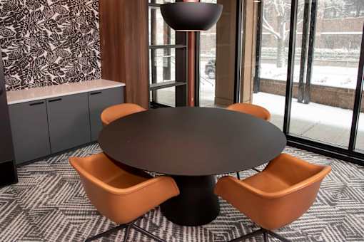 An office amenity area round table with four chairs around it.