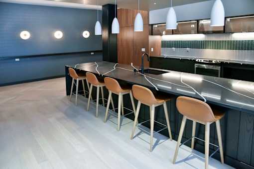 A modern kitchen with a long bar and stools.