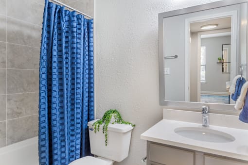 A white toilet with a blue curtain in the shower.