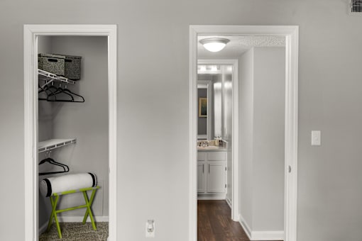 A white closet with a mirror and a chair.
