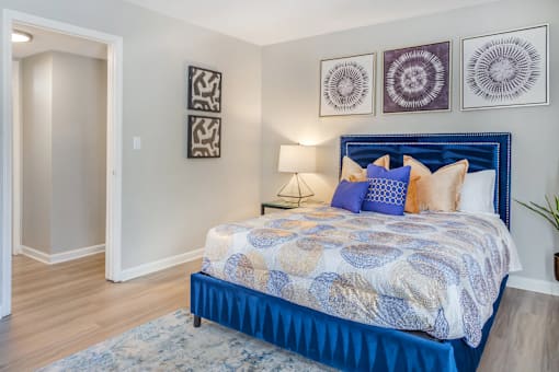 A bedroom with a blue bed and a white wall.