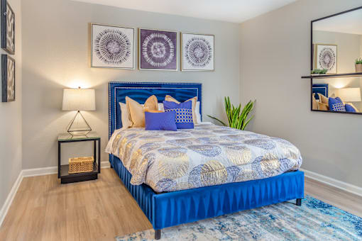 A bedroom with a blue bed and a mirror on the wall.