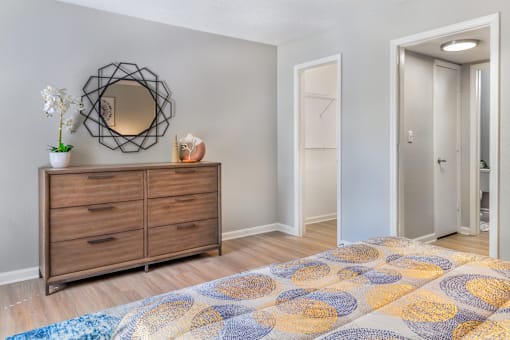 A room with a wooden dresser and a round mirror on the wall.
