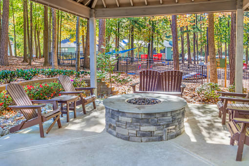 A patio with a fire pit and chairs.