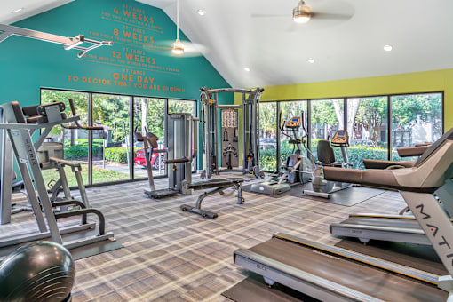A gym with a variety of equipment including treadmills, weights, and exercise machines.
