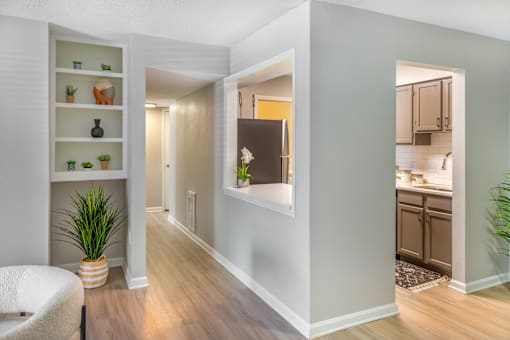 A hallway with a chair and a shelf with plants on it.