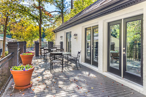 A patio with a table and chairs is surrounded by trees.