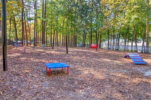 A playground with a blue slide and red and blue swings.