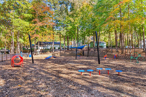A playground with a red swing set and blue and red slides.