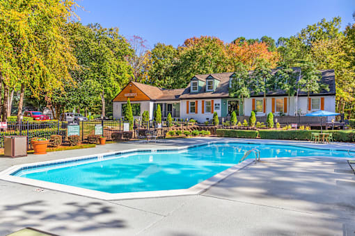 A large swimming pool in front of a house surrounded by trees.