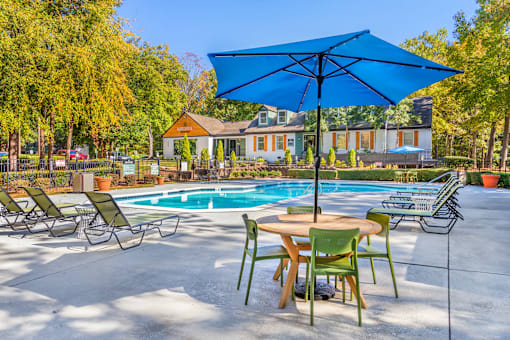 A blue umbrella is over a table with chairs around it.