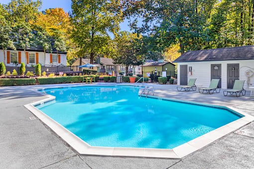 A large swimming pool surrounded by trees and houses.