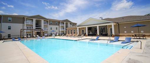 A large swimming pool surrounded by lounge chairs and umbrellas.