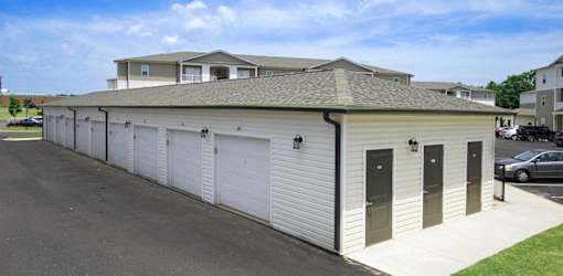 A long building with a grey roof and white garage doors.