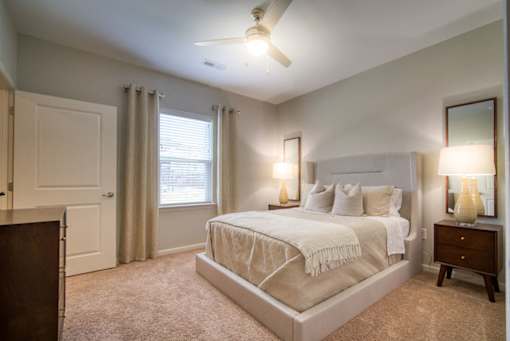 A bedroom with a bed, nightstand, and window.