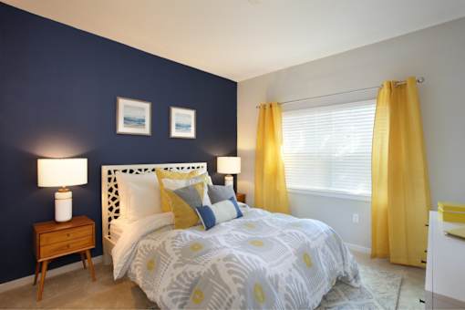 A bedroom with a white bed and yellow curtains.