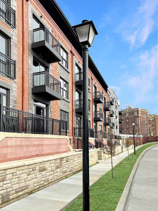 A street lamp stands on a sidewalk in front of a brick building with balconies.