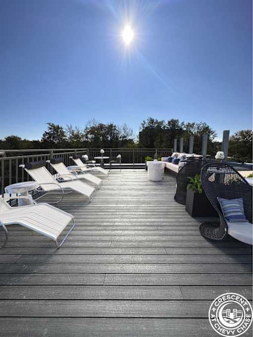 A sunny day at the rooftop deck with white lounge chairs and a table.