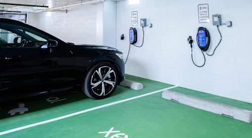 A black car is charging at a Tesla charging station.