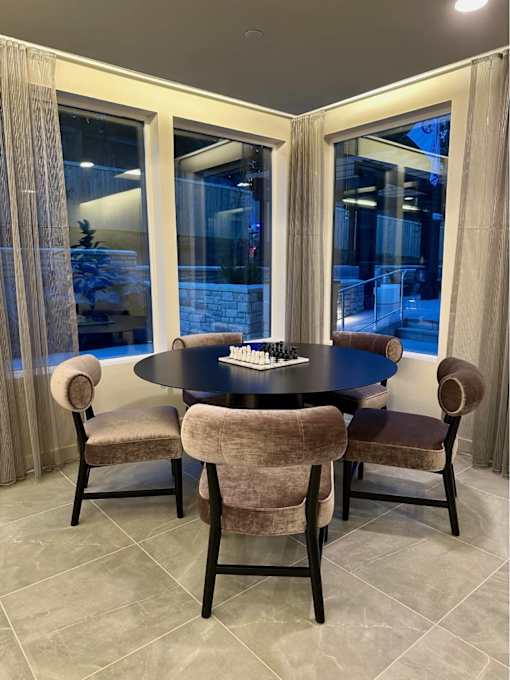 A dining table with chairs and a chess set on it.