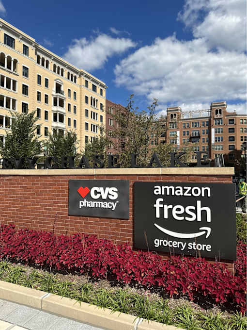 A brick wall with a CVS Pharmacy and Amazon Fresh Grocery Store sign.