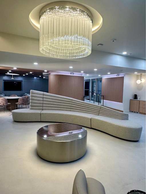 A modern living room with a curved sofa and a chandelier.