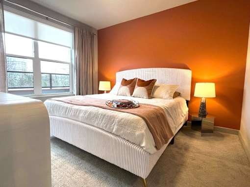 A bedroom with a large bed and two lamps.