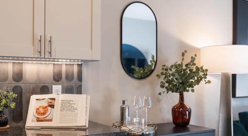 A dining table with a book, glasses, and a vase with a plant on it.