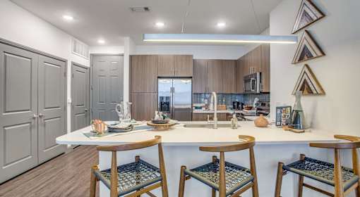 A kitchen with a white countertop and wooden chairs.