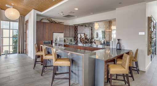 A modern kitchen with wooden chairs and a large island.