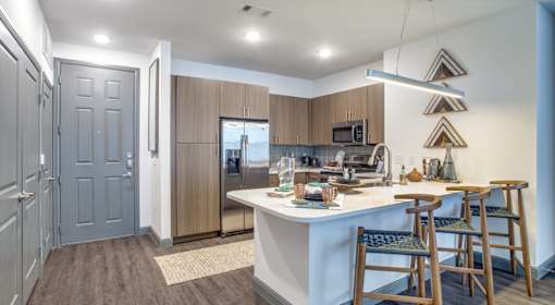 A kitchen with a white counter and wooden chairs.