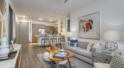 A modern living room with a grey sofa, a wooden coffee table, and a large abstract painting on the wall.