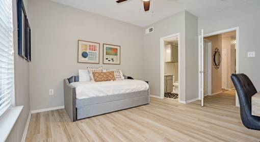 A bedroom with a bed, chair, and artwork on the wall.