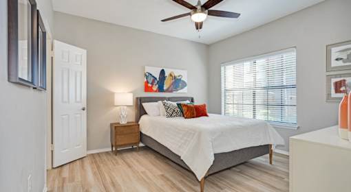 A bedroom with a bed, nightstand, and a painting on the wall.