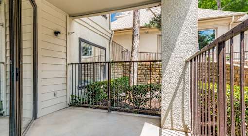 A patio with a black railing and a white wall.