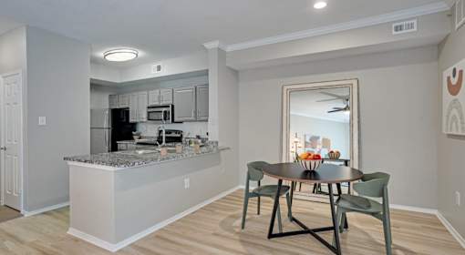 A kitchen with a table and chairs in front of a mirror.