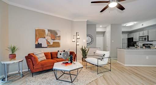 A living room with a brown couch, a white chair, and a coffee table.
