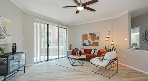 A living room with a ceiling fan and sliding glass doors.