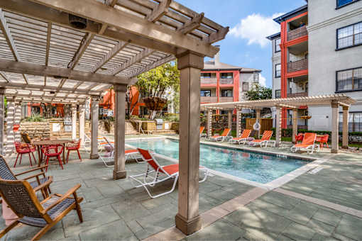 A pool area with chairs and a table.