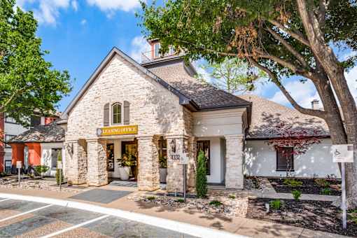 A stone building with a yellow sign that says "Leasing Office".