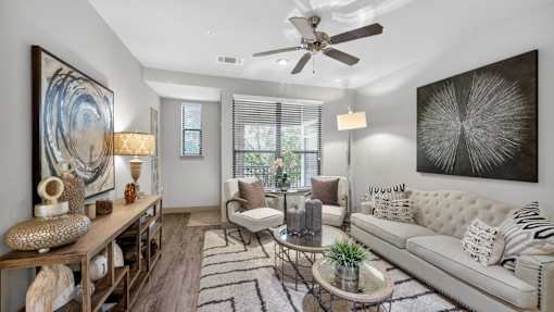 A living room with a white couch, a wooden table, and a large painting on the wall.