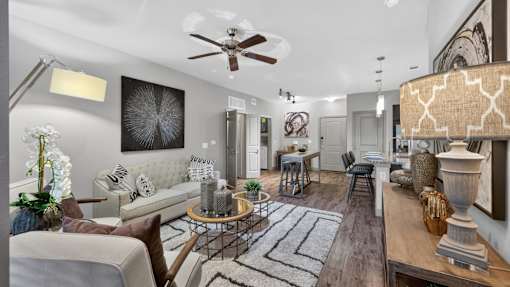 A living room with a grey couch, a coffee table, and a ceiling fan.