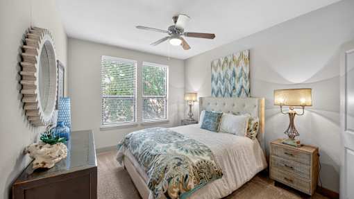 A bedroom with a bed, a dresser, a mirror, and a ceiling fan.