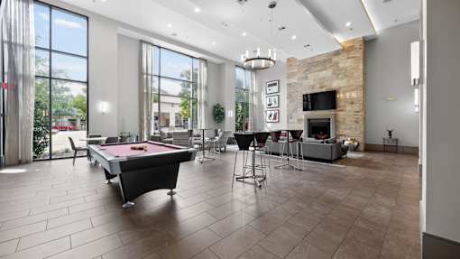 A billiard table is in the middle of a room with a fireplace and a TV.